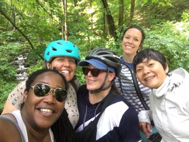 Group of women in bike helmets, piling over each other for a selfie