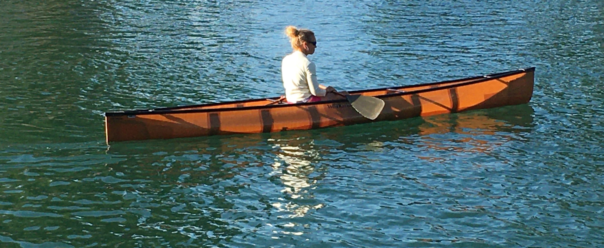 A solo paddler sits in a canoe contemplating the water