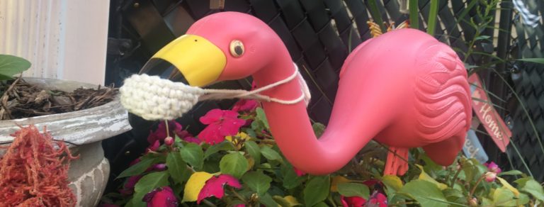 Plastic flamingo wearing a hand-crocheted face mask on its beak