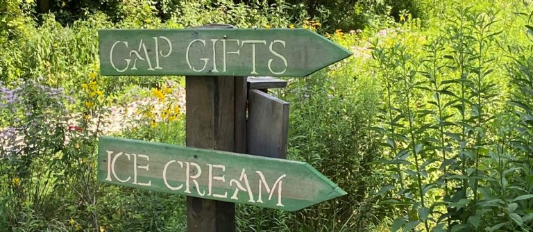 A directional sign pointing people toward a retail shop and ice cream